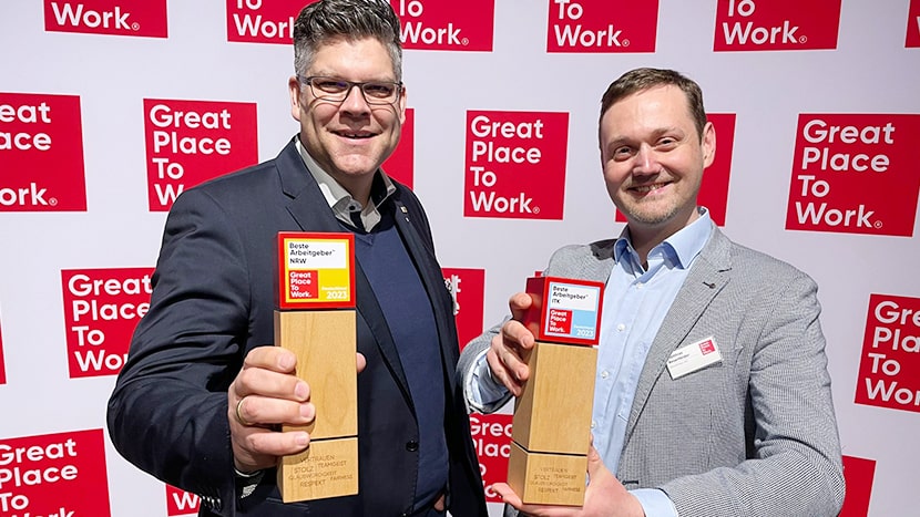 Peter Bäumer und Matthias Besenfelder halten Auszeichnungen für erfolgreiche Arbeitsplatzkultur in den Händen.