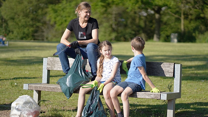 Eine Mitarbeiterin der BROCKHAUS AG sammelt gemeinsam mit ihren Kindern Müll in der Natur, verkörpert das Engagement des Unternehmens für eine saubere Umwelt.
